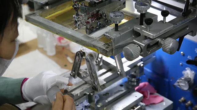 Operator applying a custom surface decoration to a glass container